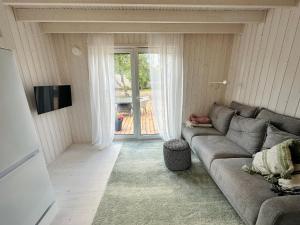 a living room with a gray couch and a television at Fully equipped new tiny-house in Kuressaare