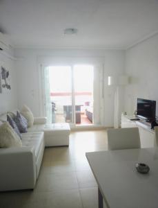 een witte woonkamer met een bank en een televisie bij Casa JC in Orihuela