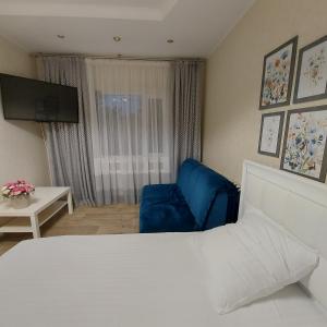um quarto de hotel com uma cama e uma cadeira azul em 2кк люкс 3-я Слободская/Кузнецкая em Mykolaiv