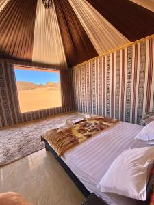 a bedroom with a bed with a view of the desert at WADi RUM ALi CAMP in Wadi Rum