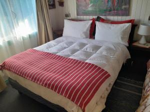 a large bed with a red and white striped blanket at Globertrotters in Castro
