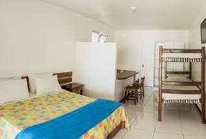 a bedroom with a bed and a table and chairs at Hotel Mundaí Praia Camping e Est para Mh in Porto Seguro