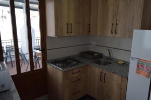 cocina con armarios de madera, fregadero y nevera en CASA DEL RIO, en Castril