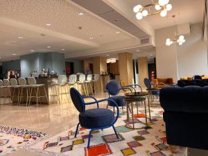 a salon with chairs and a bar in the background at Hotel Le Quercy - Sure Hotel Collection by Best Western in Brive-la-Gaillarde