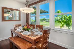 a dining room with a table and chairs and windows at Pili Mai 9G in Koloa