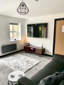 a living room with a couch and a flat screen tv at Mill Bank Apartment in Todmorden