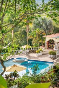 an outdoor swimming pool with umbrellas and trees at Hotel Posada Campestre San Gil in San Gil