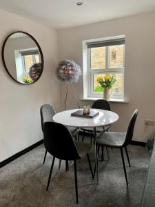 uma sala de jantar com uma mesa, cadeiras e um espelho em Mill Bank Apartment em Todmorden