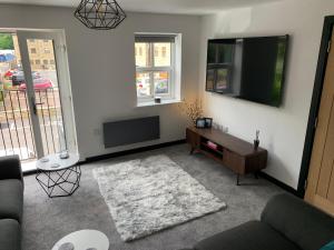 a living room with a flat screen tv and a couch at Mill Bank Apartment in Todmorden