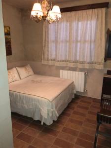 1 dormitorio con cama, ventana y lámpara de araña en Casa de Piedra la Loma, en Calar de la Santa