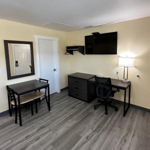 a hotel room with a desk and a table and a mirror at Relax Inn of Medford in Medford