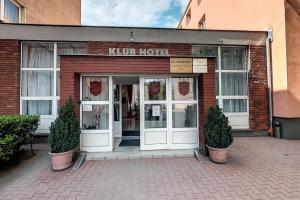 a kuhnee hotel entrance with two plants in front of it at Klub Hotel in Dunaújváros