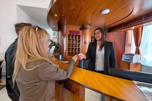 a woman standing at a counter in a bar at Klub Hotel in Dunaújváros