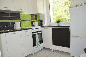 a kitchen with white cabinets and a black dishwasher at Ljus in Sopot