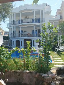 una gran casa blanca con un jardín delante de ella en Apartments Pekic, en Bar
