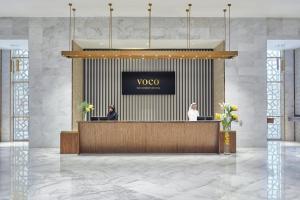 a rendering of a lobby with two people sitting at a reception desk at voco Makkah an IHG Hotel in Makkah