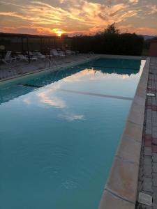 a swimming pool with a sunset in the background at Residence il Tombolo in Principina a Mare