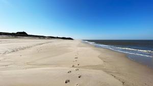 a beach with footprints in the sand and the ocean at Boutique Suites Sylt - Kliffkante - Opening August 2023 in Kampen