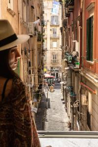 Un uomo con un cappello che guarda fuori dalla finestra in un vicolo di ES Suites a Napoli