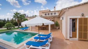 einem Pool mit Stühlen und einem Sonnenschirm neben einem Haus in der Unterkunft Casa rural, finca rústica con piscina Cas Padrins de Campos, Mallorca in Campos