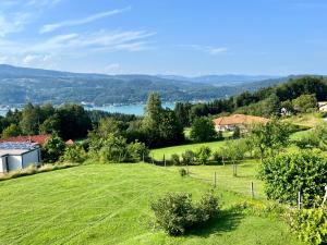 un prato verde con un lago sullo sfondo di Danny's Wörtherseeblick a Schiefling am Wörthersee