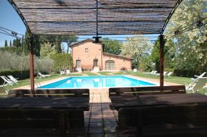 a swimming pool with benches and a building at La Casa Delle Querce in Acquaviva