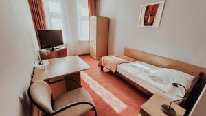 a small room with a bed and a desk and chair at Hotel Marco in Będzin