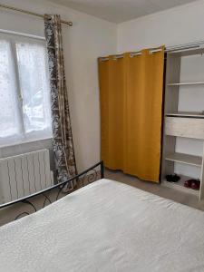 a bedroom with a bed and a yellow curtain at Chez Laeti appartement type F2 in Fécamp