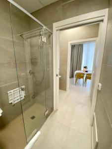 a bathroom with a glass shower and a dining room at BeeApartments in Bari