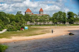 a man standing on a beach next to a body of water at Fully equipped new tiny-house in Kuressaare