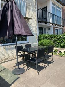 贊德沃特的住宿－El Sol Zandvoort，庭院内桌椅和遮阳伞
