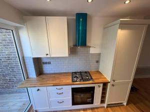 a kitchen with white cabinets and a stove top oven at One Bed Flat With Garden in London