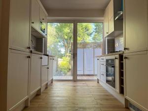 a large kitchen with a large window and a kitchen with white cabinets at One Bed Flat With Garden in London