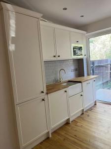 a kitchen with white cabinets and a sink at One Bed Flat With Garden in London