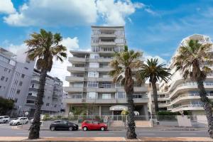 um parque de estacionamento com palmeiras em frente a um edifício em Beachfront Luxury Family Escape em Cidade do Cabo