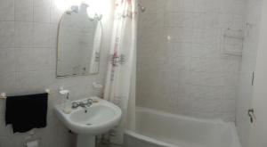 a white bathroom with a sink and a mirror at La Recova de La Boca in Buenos Aires
