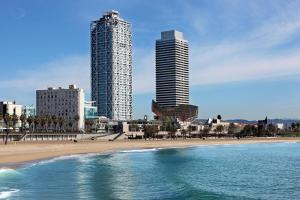 twee hoge gebouwen op een strand naast de oceaan bij Hotel Arts Barcelona in Barcelona