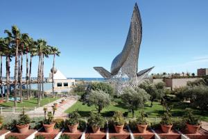 uma vista para um parque com uma estátua e palmeiras em Hotel Arts Barcelona em Barcelona