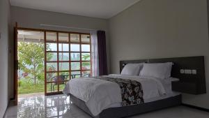 a bedroom with a large bed and a sliding glass door at Mountain Ecolodge in Gubukklakah