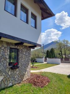a house with a stone wall next to a driveway at Bosanska kuća Emina in Bihać