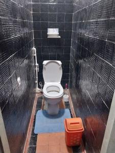 een badkamer met een toilet in een zwart betegelde muur bij Welcome Guest House in Tokmok