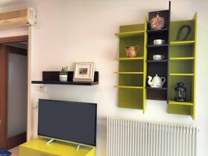 a living room with a tv and green shelves at Finestre Verdi appartamento con parcheggio in Ronchi dei Legionari