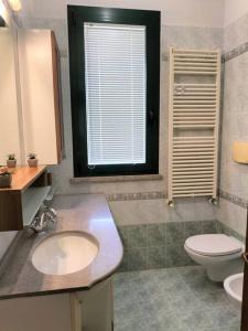 a bathroom with a sink and a toilet and a window at Finestre Verdi appartamento con parcheggio in Ronchi dei Legionari