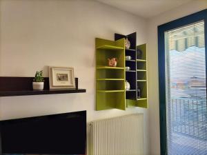 ein Wohnzimmer mit grünen Regalen und einem TV in der Unterkunft Finestre Verdi appartamento con parcheggio in Ronchi dei Legionari