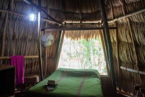 a room with a bed and a window in a hut at Alice Guesthouse in El Remate