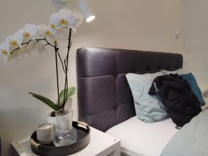 a vase with flowers on a table next to a bed at Modern Courtyard Condo in Liepāja