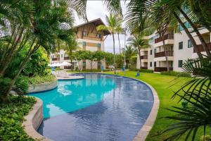 una piscina en un complejo con palmeras en Flat térreo 2 quartos no Marulhos Resort - Beira mar Muro Alto en Porto De Galinhas
