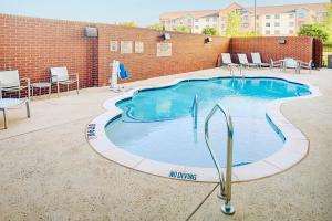a large swimming pool with chairs and a brick wall at SpringHill Suites by Marriott Dallas Lewisville in Lewisville