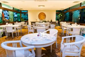 un comedor con mesas blancas y sillas blancas en Flat térreo 2 quartos no Marulhos Resort - Beira mar Muro Alto en Porto De Galinhas