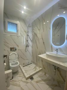 ein Badezimmer mit einem Waschbecken, einem WC und einem Spiegel in der Unterkunft Valentina Hotel in Paralia Katerinis